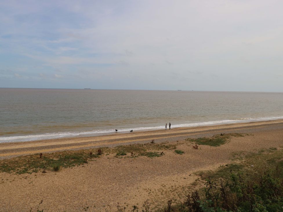 A beach with people walking along the shoreline at The Mill House Gardens