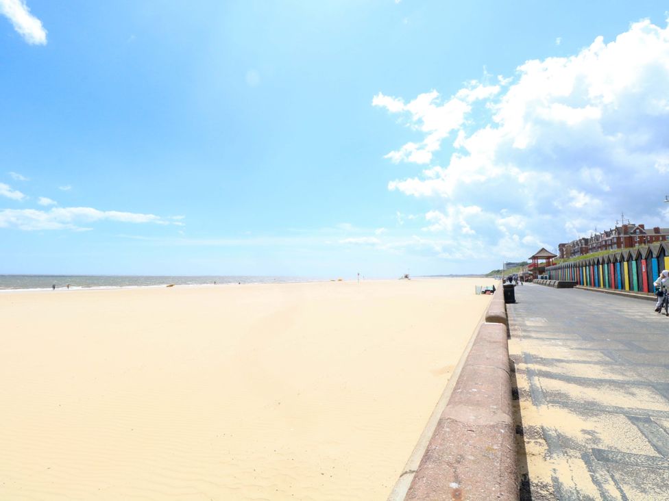 A beach scene with a boardwalk and colorful beach huts at The Mill House Gardens 