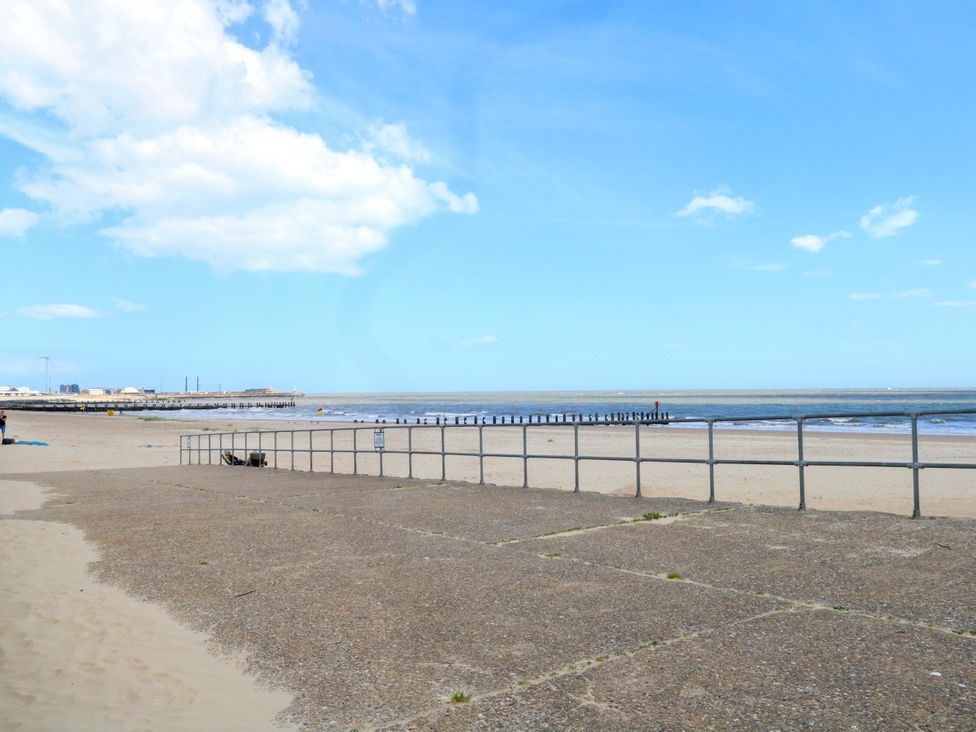 A beach view with sand, water, pier and railings at The Mill House Gardens 