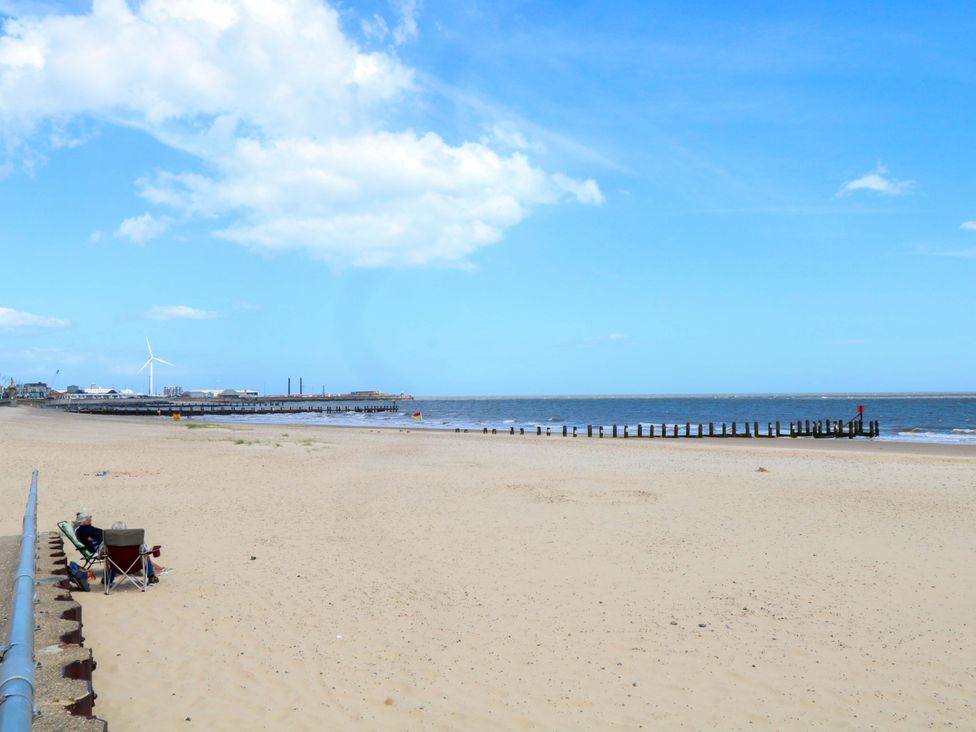 A beach with a pier and chairs at The Mill House Gardens in 