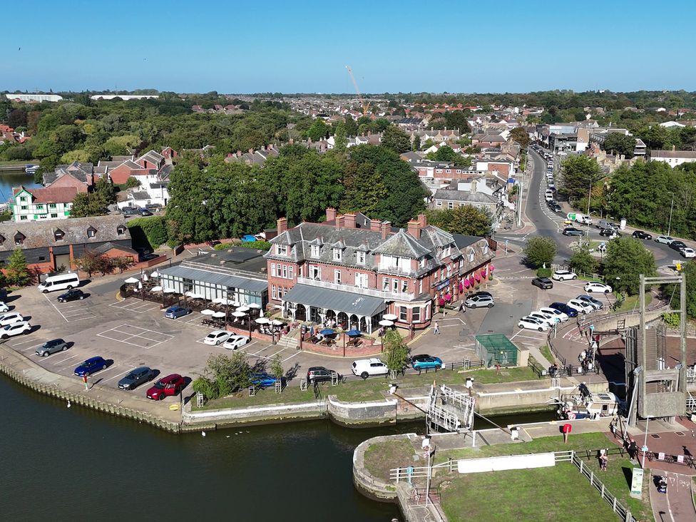 An aerial view of a building with a parking lot and river at The Mill House Gardens in Oulton Broad