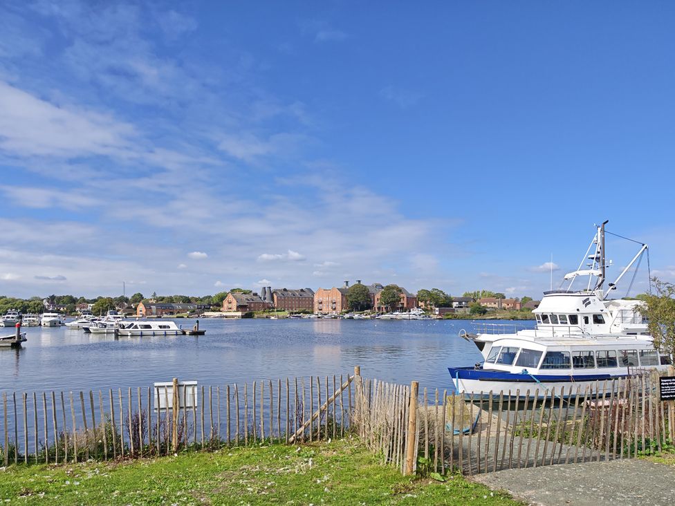 A view of boats on water and buildings in the background at The Mill House Gardens Oulton Broad