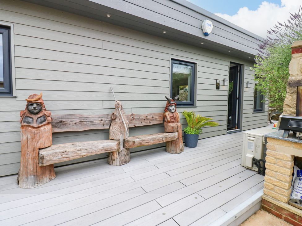 An outdoor area with a wooden bench and carvings at Caesars Lodge in Houghton Bank near Heighington