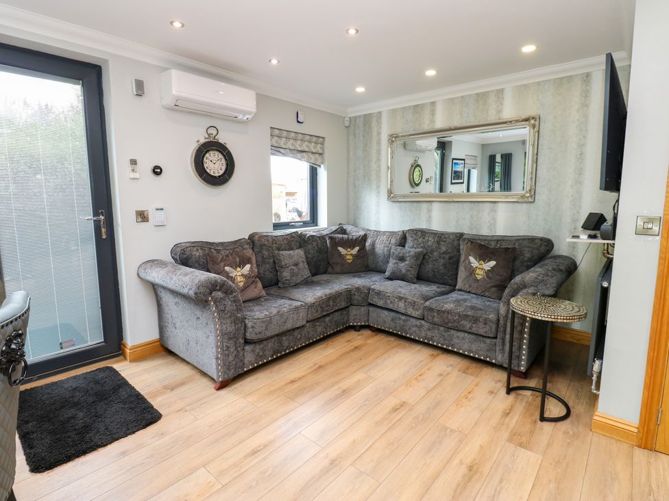 A living room with a sofa and a clock at Caesars Lodge, Houghton Bank near Heighington