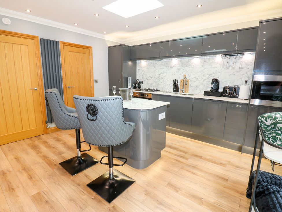 A kitchen with bar stools and kitchen island at Caesars Lodge in Houghton Bank near Heighington