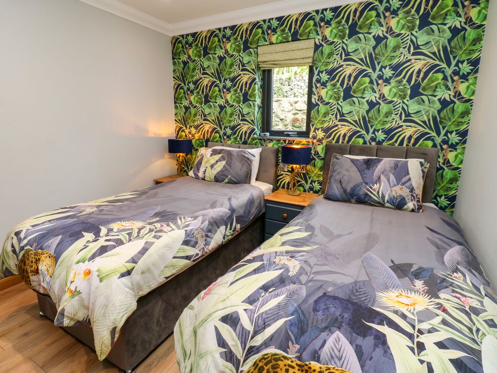 A bedroom with two beds and floral wallpaper at Caesars Lodge in Houghton Bank near Heighington