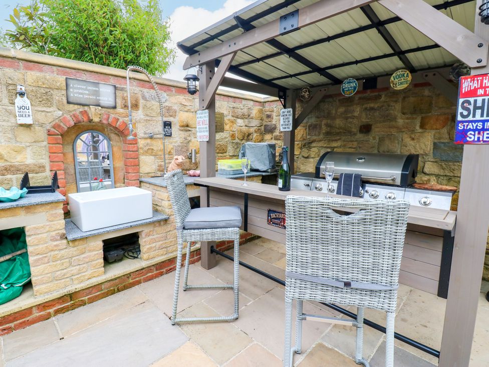 An outdoor kitchen with a barbecue grill and bar stools at Caesars Lodge in Houghton Bank near Heighington