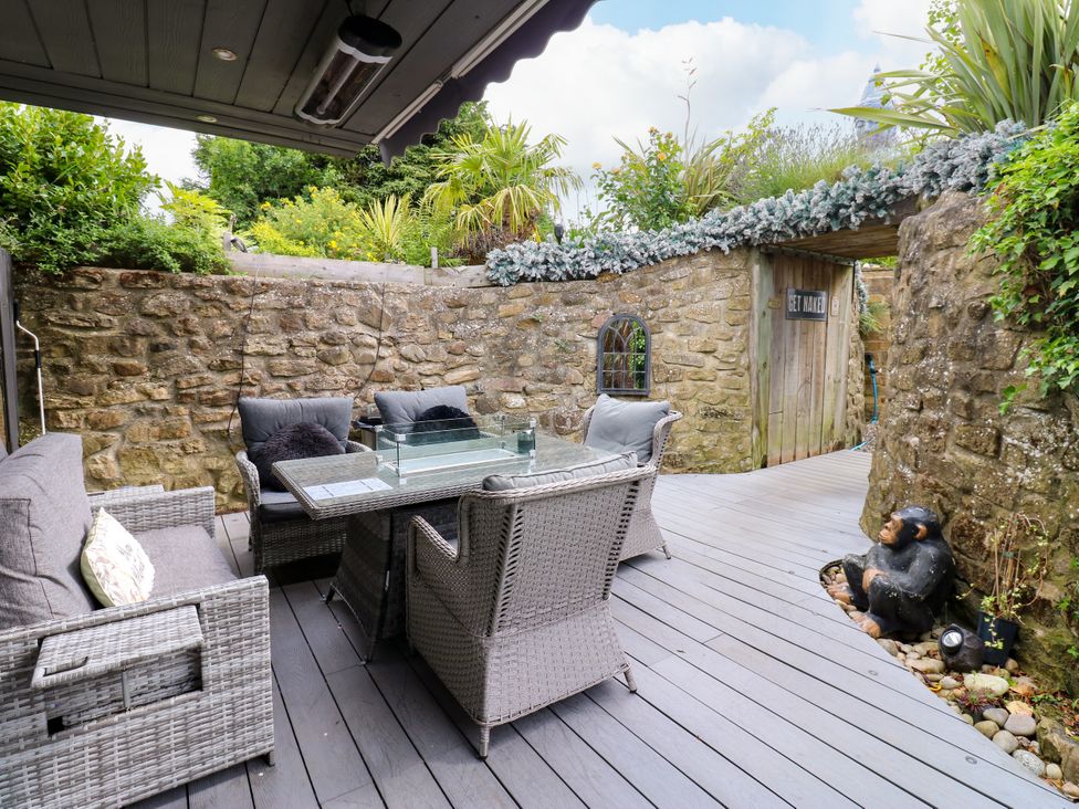 An outdoor seating area with a glass table and stone wall at Caesars Lodge Houghton Bank near Heighington
