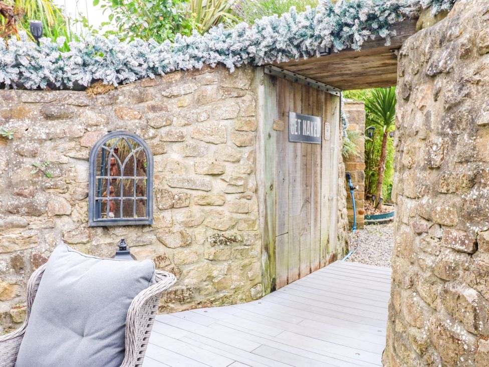 An outdoor area with a stone wall and a door at Caesars Lodge Houghton Bank near Heighington