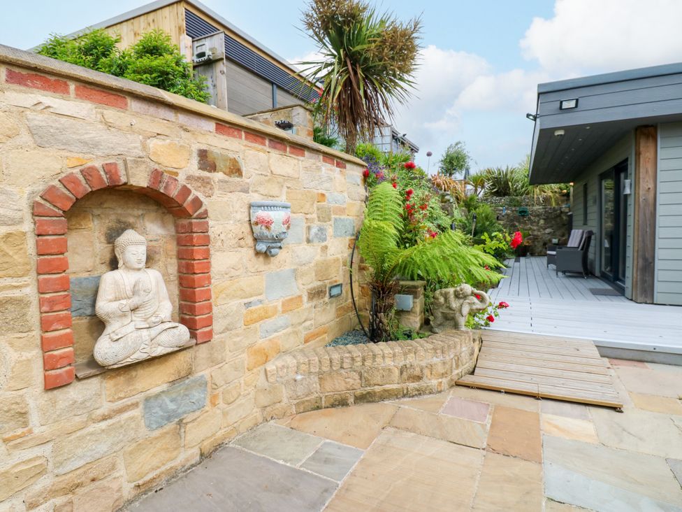 A garden with a stone wall and Buddha statue at Caesars Lodge Houghton Bank near Heighington