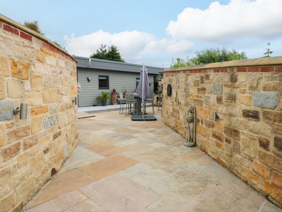 An outdoor area with a stone wall and patio furniture at Caesars Lodge in Houghton Bank near Heighington