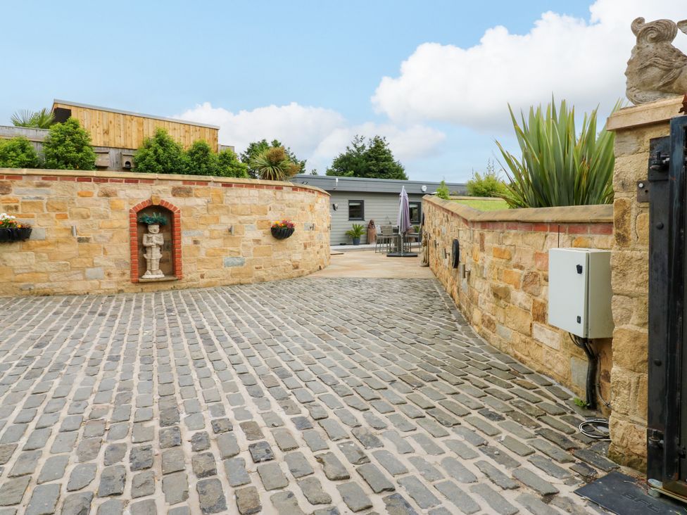An outdoor area with a cobblestone pathway and stone walls at Caesars Lodge Houghton Bank near Heighington