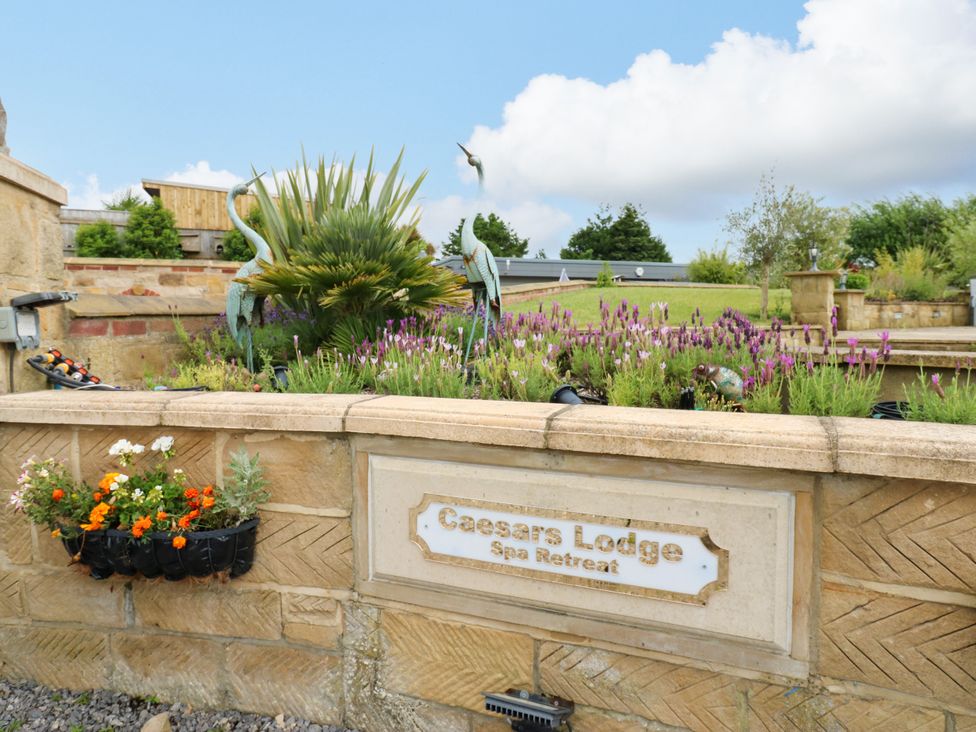 A garden with decorative plants and a sign at Caesars Lodge Spa Retreat Houghton Bank near Heighington