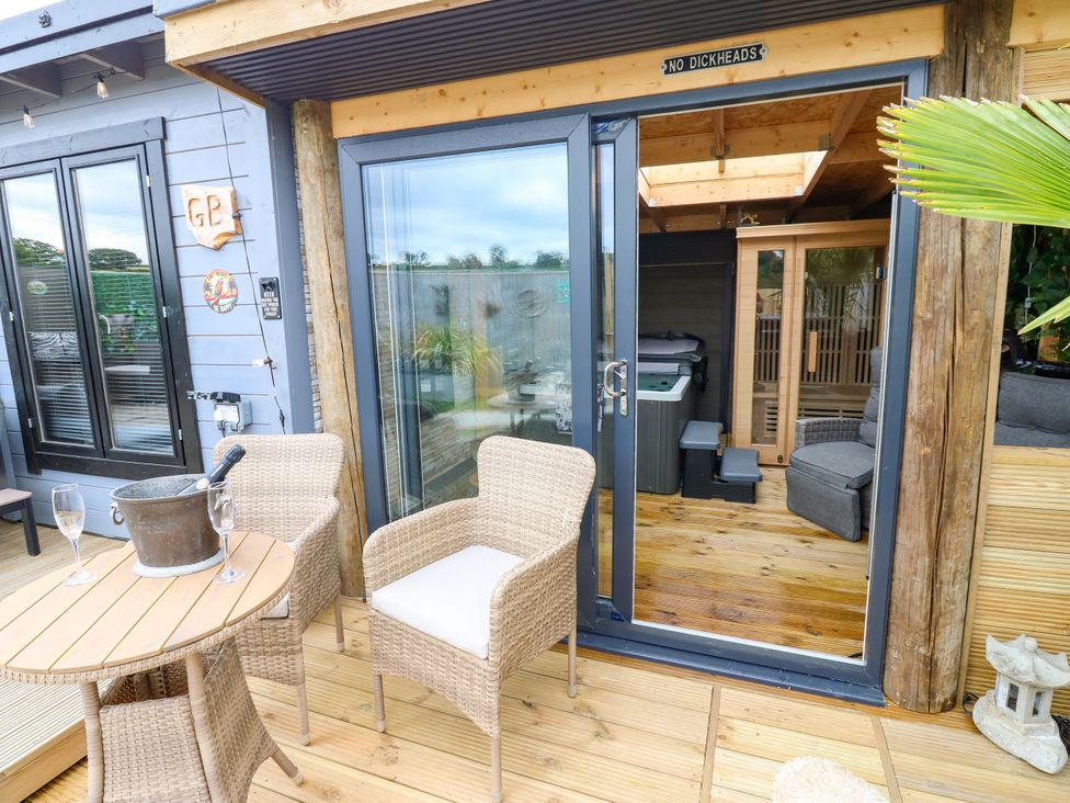 An outdoor area with chairs and a table near a sauna and hot tub at Black River Houghton Bank near Heighington