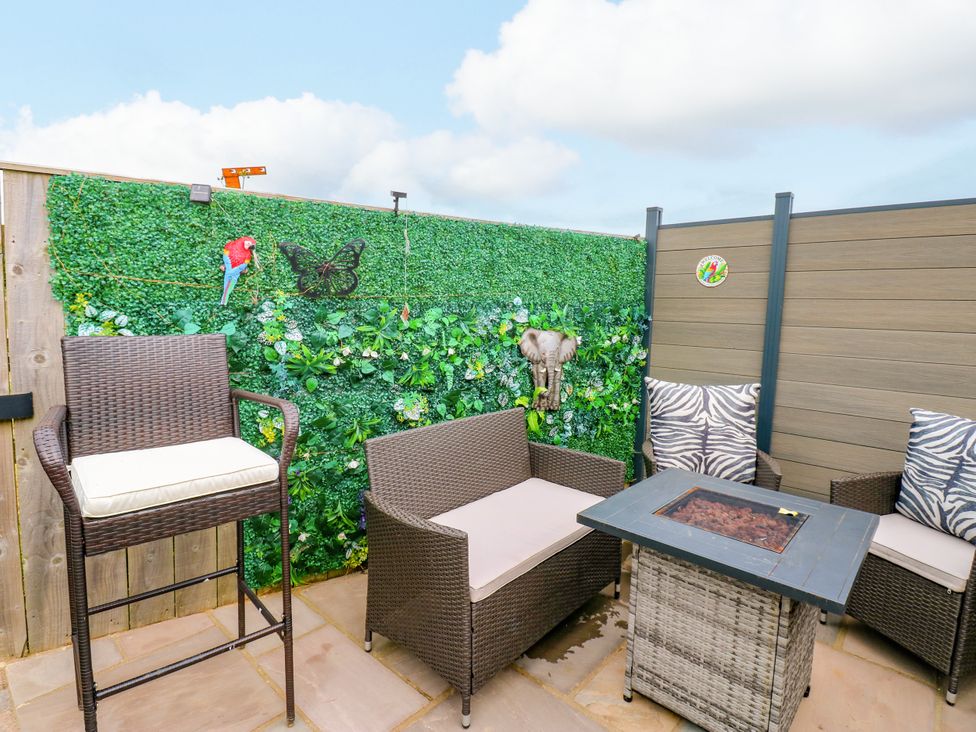 An outdoor seating area with sofas and a fire pit table at Black River in Houghton Bank near Heighington