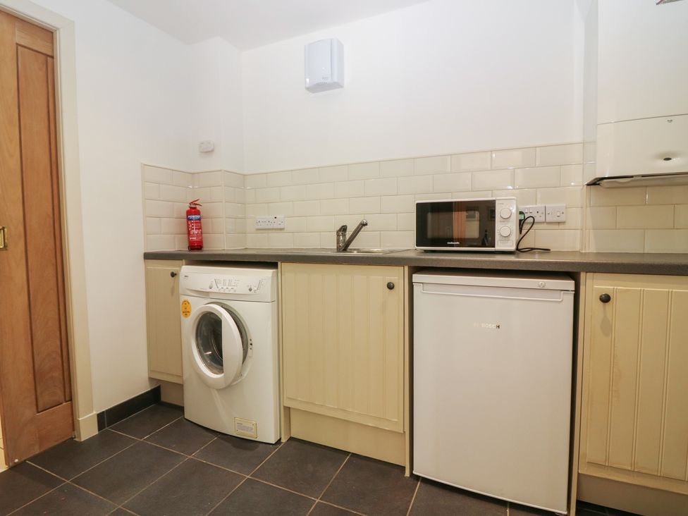 A kitchen with a washing machine, microwave, and fridge at Hollybank Barn near Melrose