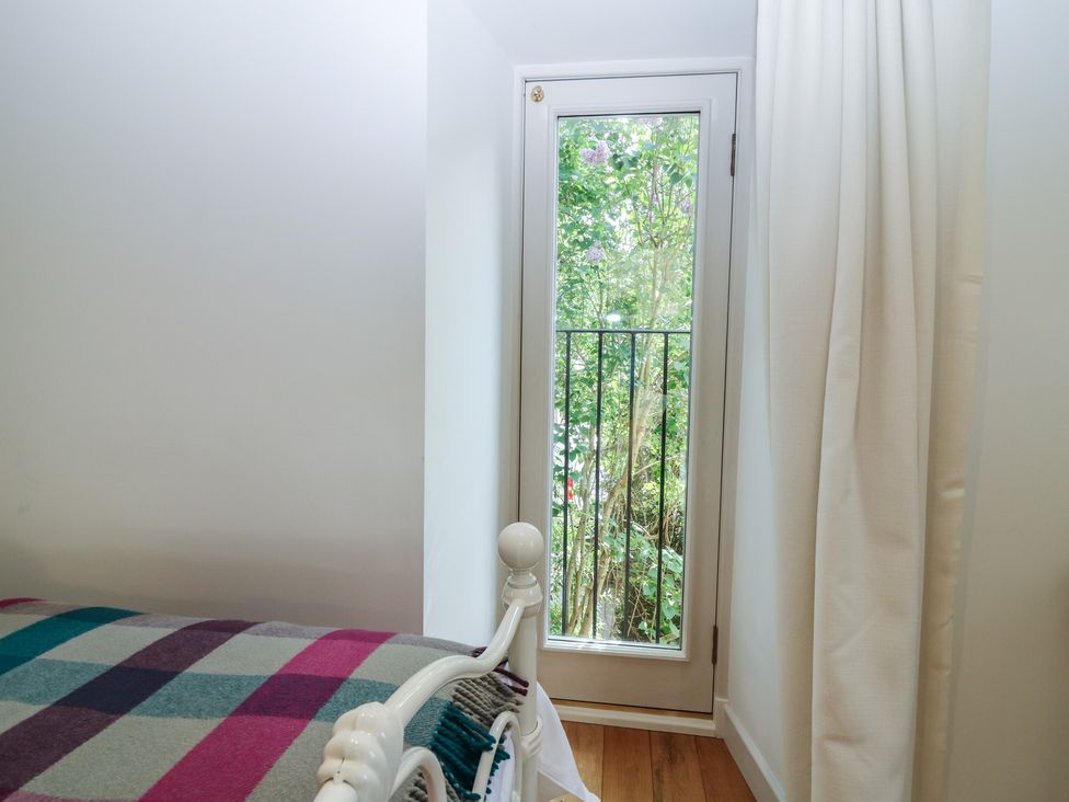 A bedroom with a bed and window overlooking greenery at Hollybank Barn near Melrose