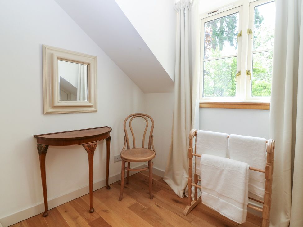 A room with a mirror, table, chair, and towel rack at Hollybank Barn near Melrose