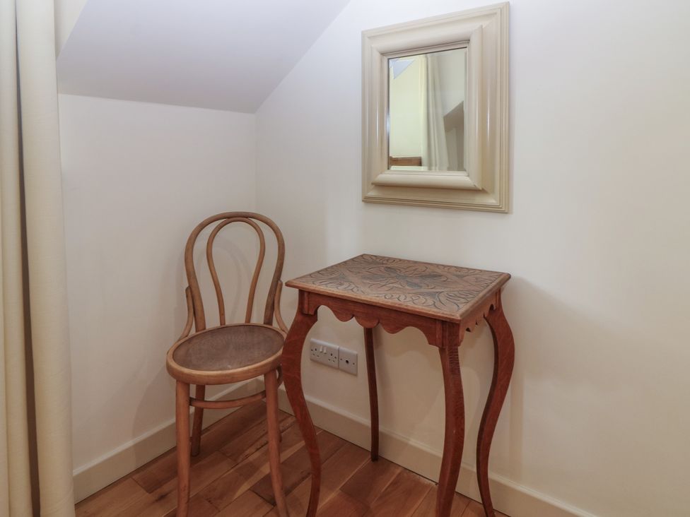 A chair and a small table with a mirror in a nook at Hollybank Barn near Melrose