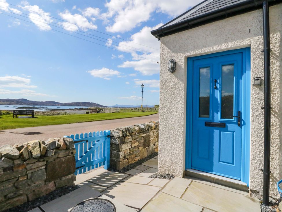 A blue door and gate with a stone wall at Post Cottage in Arisaig