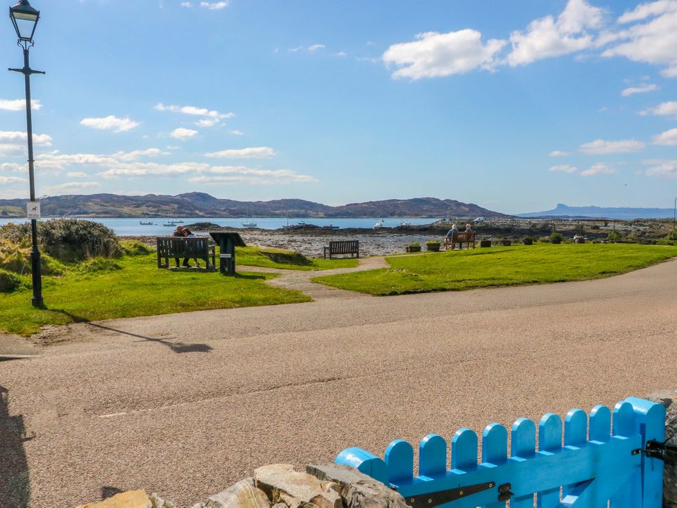 A view of the sea and mountains with benches and a pathway at Post Cottage in Arisaig