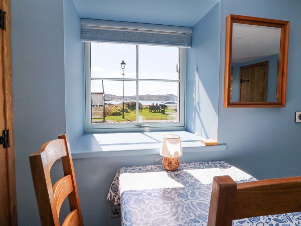 A dining area with a view from the window at Post Cottage in Arisaig