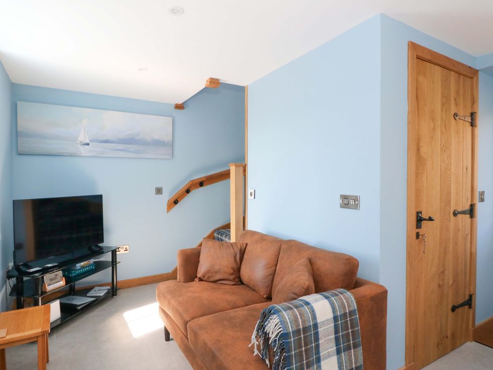 A living room with a sofa and television at Post Cottage in Arisaig