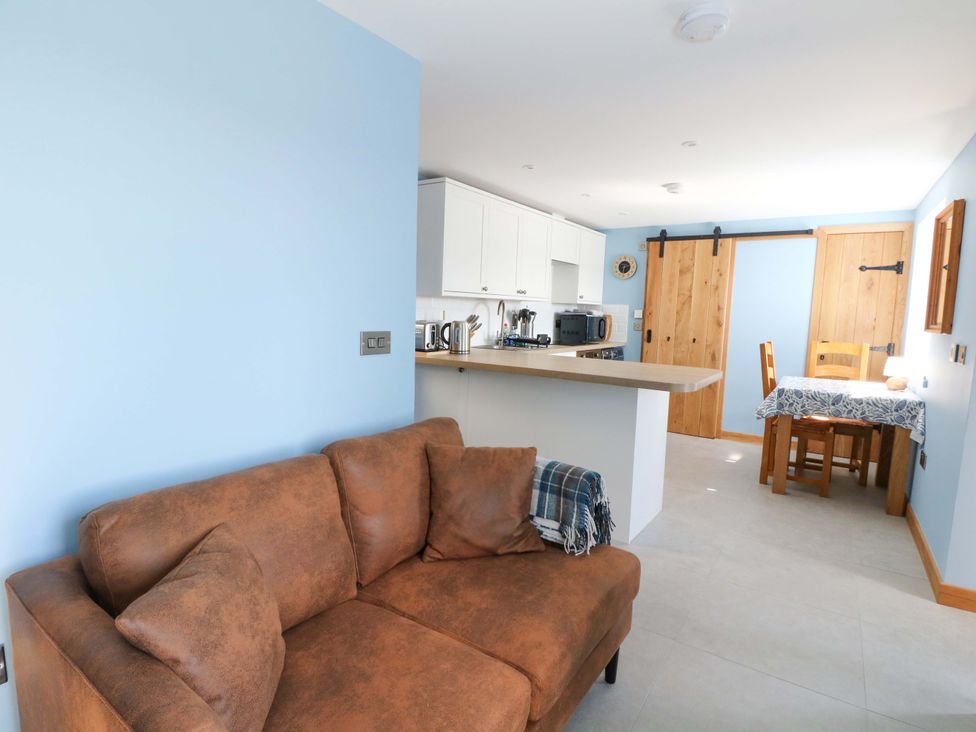 A living room with a sofa and a dining area at Post Cottage in Arisaig