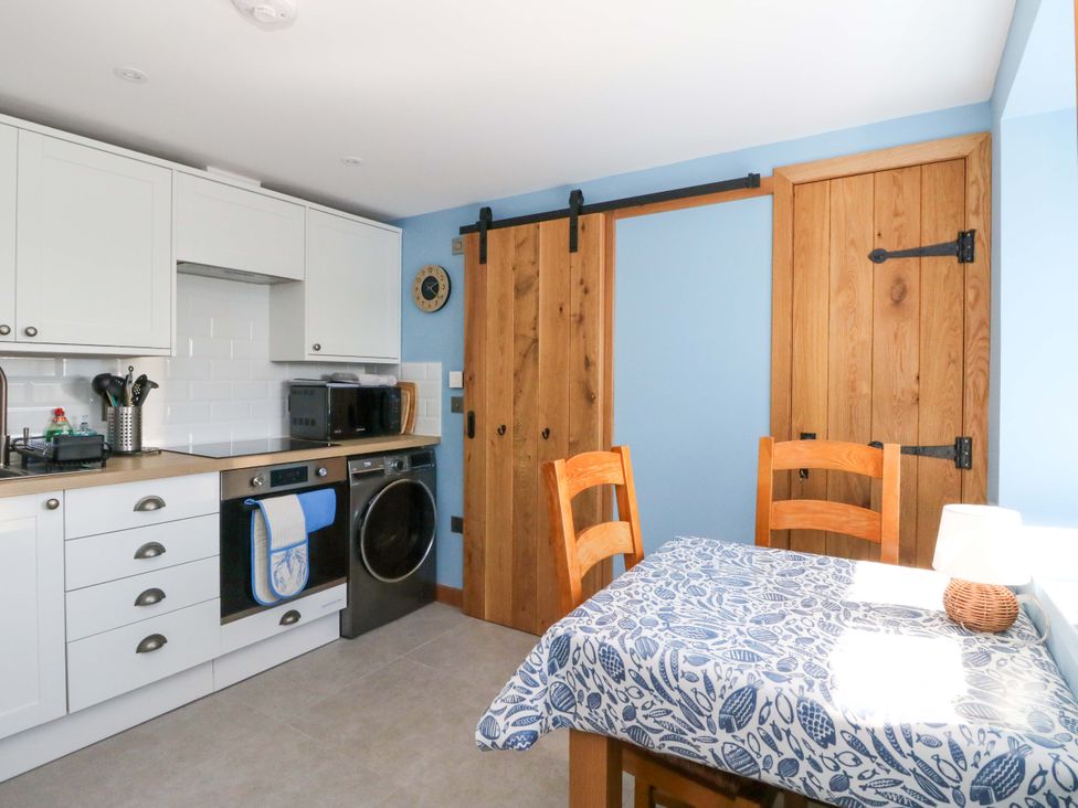 A kitchen with appliances and a dining table at Post Cottage in Arisaig