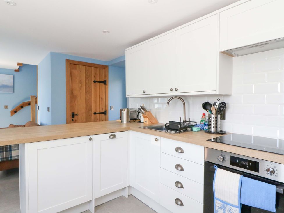 A kitchen with cabinets and a wooden countertop at Post Cottage in Arisaig