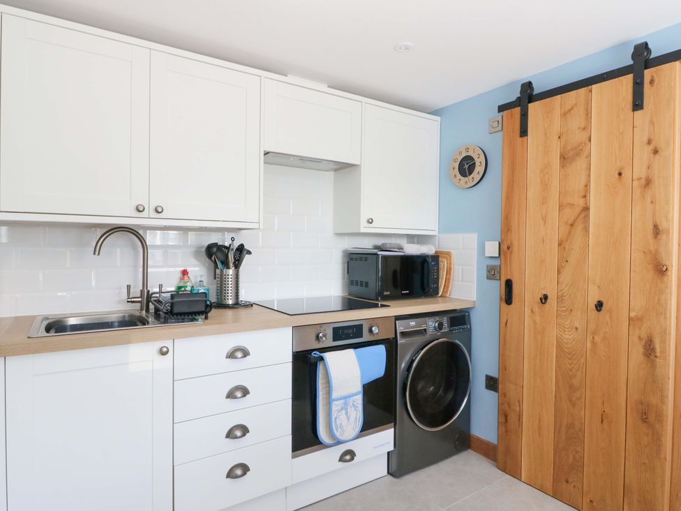 A kitchen with a sink, microwave, and washing machine at Post Cottage in Arisaig
