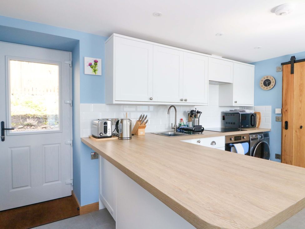 A kitchen with a wooden countertop and appliances at Post Cottage in Arisaig