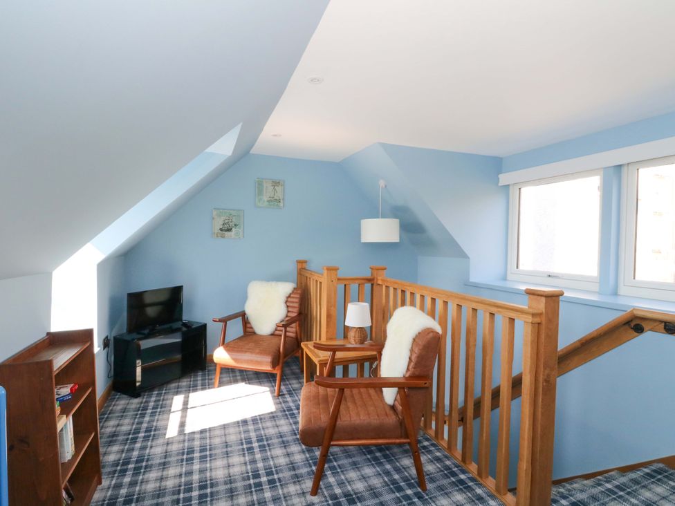 A landing with armchairs and a television at Post Cottage in Arisaig