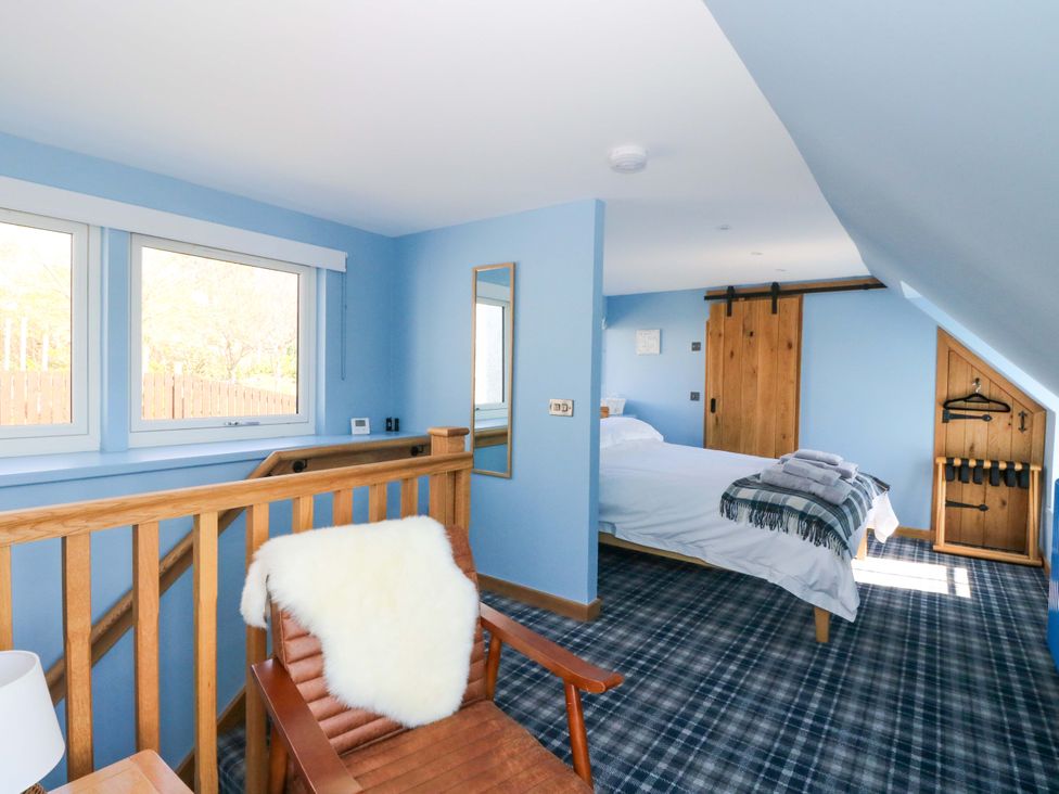 A bedroom with a bed and windows at Post Cottage in Arisaig