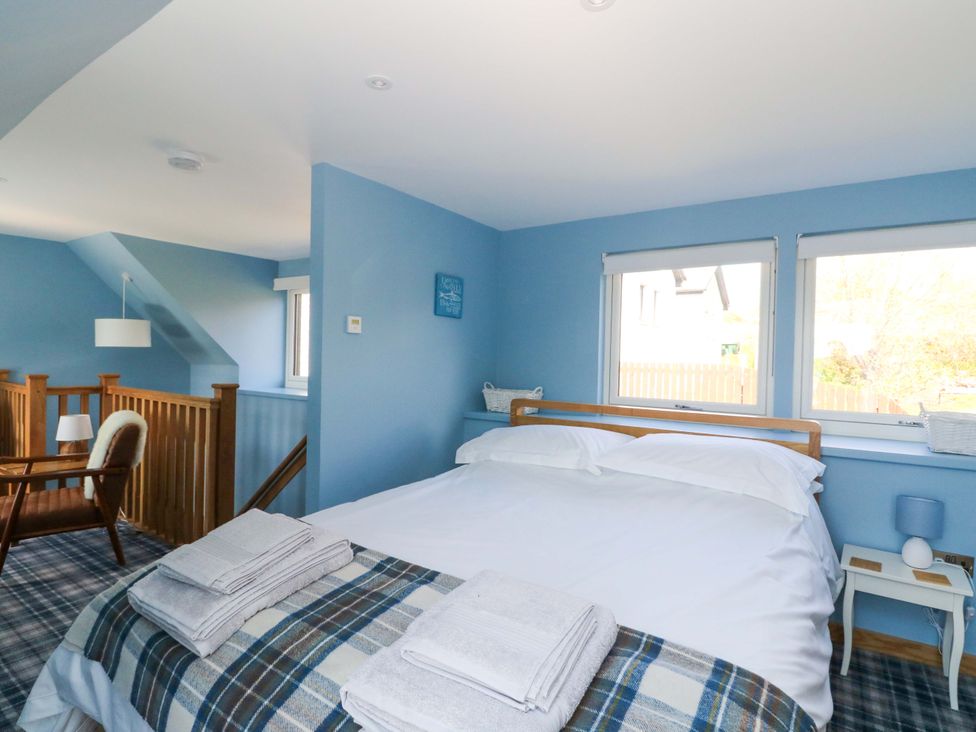 A bedroom with a bed and a chair at Post Cottage in Arisaig