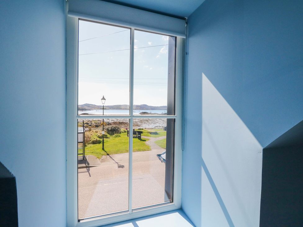 A window with a view of a pathway and water at Post Cottage in Arisaig