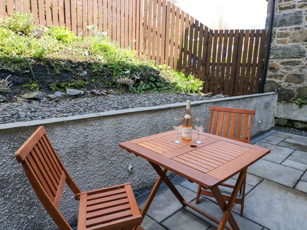 A table and chairs with a bottle and glasses in an outdoor area at Post Cottage Arisaig