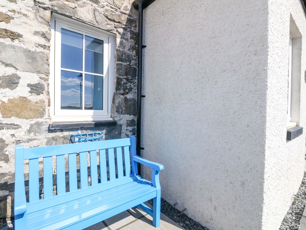 A blue bench and window on a stone wall at Post Cottage in Arisaig