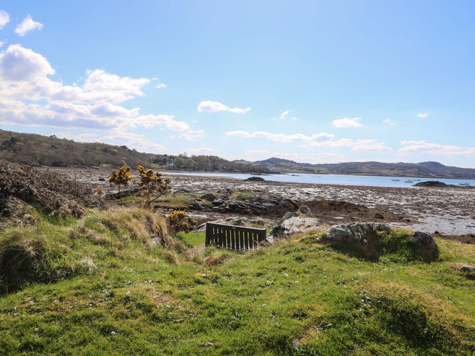 A scenic outdoor view with a bench overlooking a water area at Post Cottage Arisaig