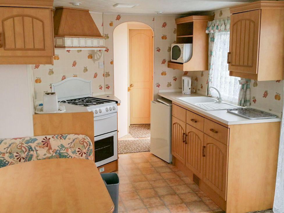 A kitchen with cabinets, stove, sink, and refrigerator at Number 186 Owens caravan park Abergele