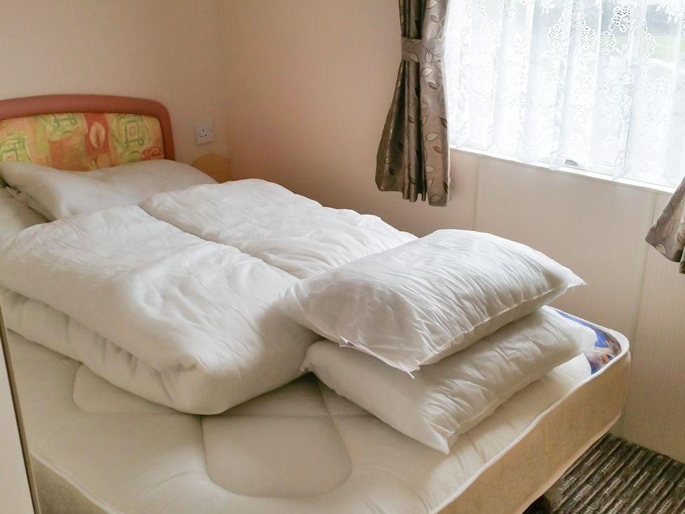 A bedroom with a bed and pillows at Number 186 Owens caravan park in Abergele