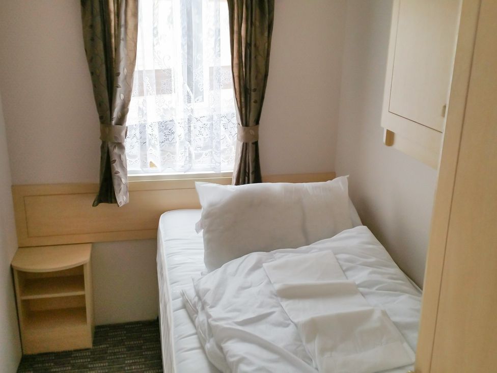 A bedroom with a bed and window at Number 186 Owens caravan park in Abergele