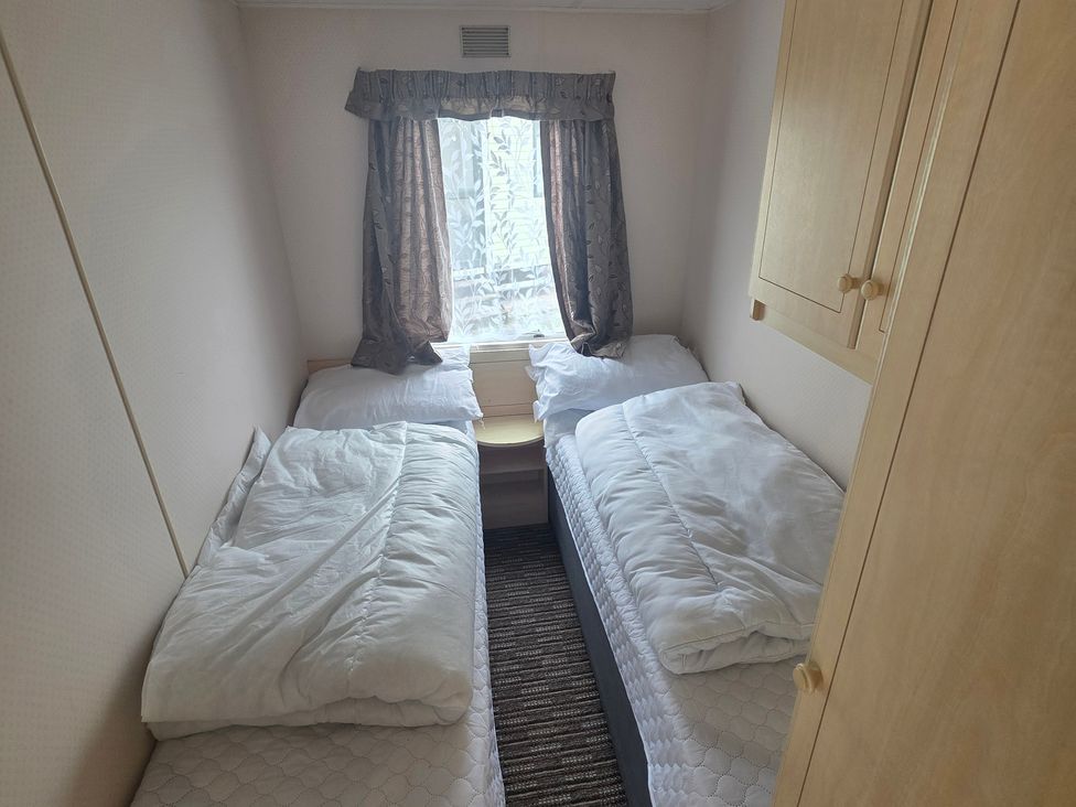 A bedroom with two single beds and a window at Number 186 Owens Caravan Park in Abergele