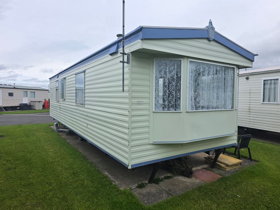 A caravan with windows and grass at Number 186 Owens Caravan Park, Abergele