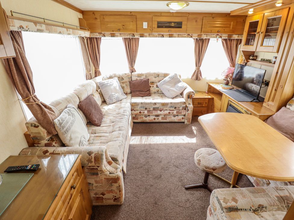 A living room with a sofa and a television at Caravan 25 in Skegness
