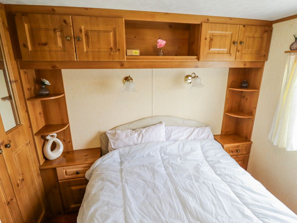 A bedroom with a bed and wooden storage at Caravan 25 in Skegness
