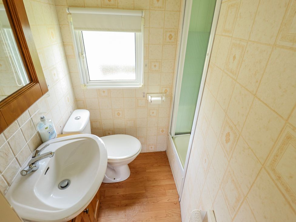 A bathroom with a toilet, sink, and shower at Caravan 25 in Skegness