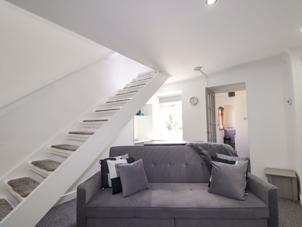 A living room with a sofa and staircase at 4A Carny Street Macduff