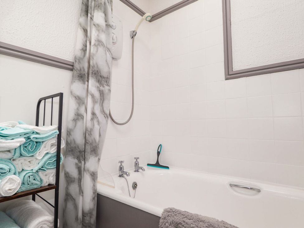 A bathroom with a bathtub and towels at 4A Carny Street, Macduff