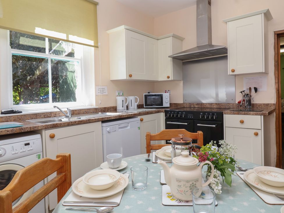 A kitchen with appliances and dining table at The Old Stables in Gloucester
